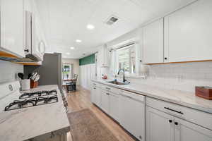 Kitchen featuring white appliances, a sink, light wood-style flooring, white cabinets, and recessed lighting