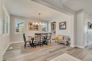Dining area with light wood-like laminate floors, a chandelier, and baseboards