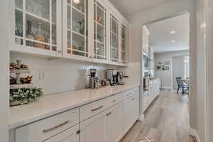 Bar area with backsplash, light wood-like laminate flooring, baseboards, and recessed lighting