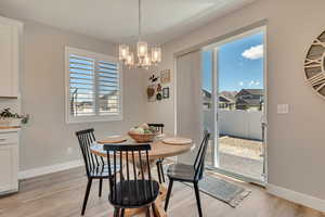 Dining area with plenty of natural light, light wood-like laminate floors, and a chandelier