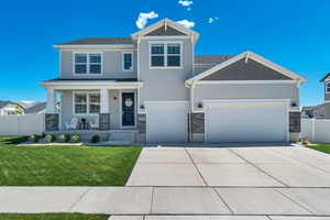 Craftsman-style home featuring a porch, driveway, an attached garage, and stone siding