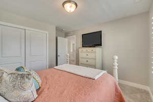 Bedroom with carpet flooring, a closet, and baseboards