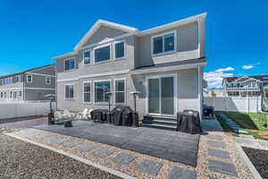 Back of house with stucco siding, a patio area, a fenced backyard, and entry steps