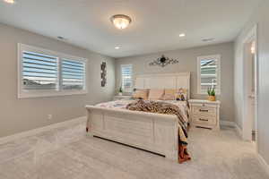Bedroom featuring light colored carpet, multiple windows, baseboards, and recessed lighting