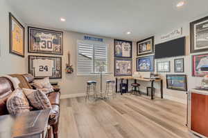 Den area featuring wood-like laminate floors, recessed lighting, and baseboards