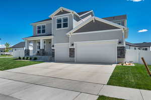 Craftsman-style house featuring an attached garage, concrete driveway, a porch, and stone siding
