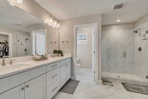 3/4 bath with toilet, euro glass shower, double vanity, and recessed lighting
