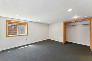Unfurnished bedroom featuring baseboards, recessed lighting, a closet, and dark colored carpet