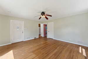Living room with a ceiling fan, light wood-style floors, baseboards, and crown molding
