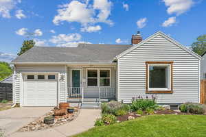View of front facade with covered porch, driveway, a garage, a chimney, and a front yard