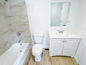 Bathroom featuring wood finished floors, toilet, vanity, and shower / bath combination