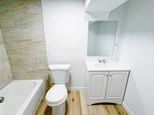 Full bath featuring wood finished floors, toilet, vanity, and baseboards