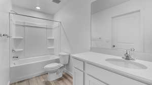 Bathroom featuring wood finished floors, toilet, vanity, shower / washtub combination, and baseboards