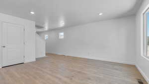 Basement featuring light wood finished floors, baseboards, healthy amount of natural light, and recessed lighting