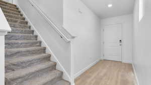 Foyer entrance featuring stairs, light wood-type flooring, baseboards, and recessed lighting