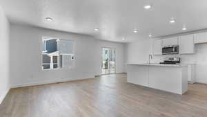 Kitchen with stainless steel appliances, a sink, light wood finished floors, recessed lighting, and white cabinetry