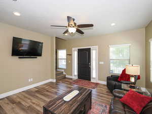 Living area featuring wood finished floors, ceiling fan, baseboards, and recessed lighting