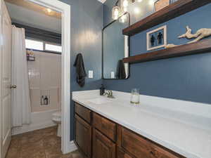 Bathroom featuring toilet, vanity, and shower / bath combo