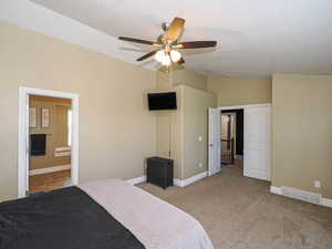 Bedroom featuring vaulted ceiling, a textured ceiling, carpet floors, baseboards, and a ceiling fan