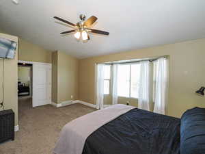 Bedroom with carpet flooring, vaulted ceiling, baseboards, and ceiling fan