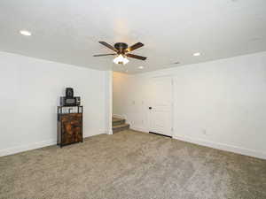 Carpeted spare room featuring a ceiling fan, recessed lighting, baseboards, and stairs