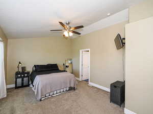 Bedroom with light carpet, baseboards, ceiling fan, and vaulted ceiling