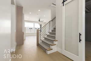 Stairs featuring wood finished floors, recessed lighting, a barn door, a ceiling fan, and baseboards