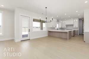 Kitchen with a chandelier, light wood-type flooring, tasteful backsplash, light countertops, and a sink