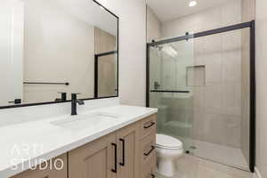 Bathroom with toilet, vanity, a stall shower, and recessed lighting