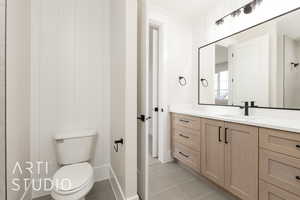 Bathroom with toilet, vanity, tile patterned flooring, and baseboards