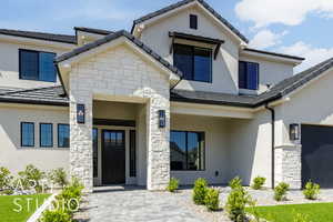 Property entrance with stone siding, stucco siding, and a tiled roof