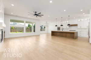 Kitchen with open floor plan, ceiling fan, backsplash, a fireplace, and white cabinetry