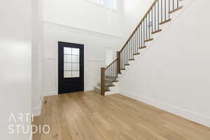 Foyer featuring light wood-style flooring, stairs, and a high ceiling