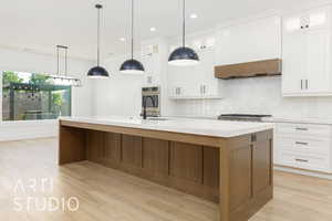Kitchen featuring a kitchen island with sink, backsplash, white cabinets, light wood-style flooring, and recessed lighting