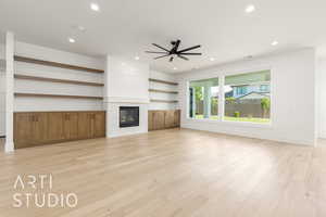 Unfurnished living room featuring a ceiling fan, recessed lighting, light wood-type flooring, a tiled fireplace, and baseboards
