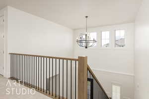 Hall featuring a chandelier, an upstairs landing, wainscoting, and a decorative wall