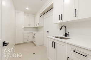 Washroom featuring washer hookup, baseboards, cabinet space, light tile patterned floors, and recessed lighting