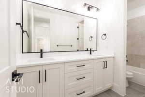 Bathroom with double vanity, toilet, tile patterned floors, and  shower combination