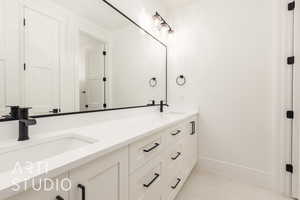 Bathroom featuring baseboards, tile patterned floors, and double vanity