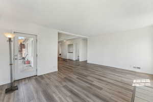 Unfurnished living room with baseboards, visible vents, and wood finished floors