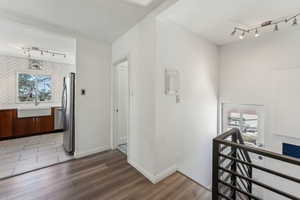 Corridor with track lighting, a sink, a healthy amount of sunlight, and light wood-type flooring