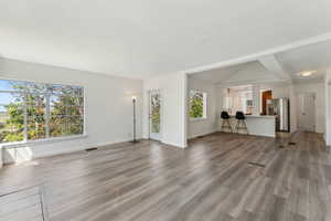 Unfurnished living room featuring visible vents, baseboards, and wood finished floors