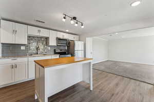 Kitchen featuring stainless steel appliances, white cabinetry, a sink, and tasteful backsplash