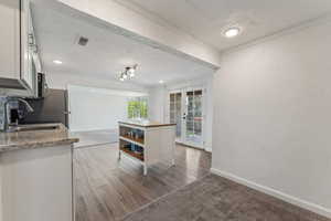 Kitchen featuring crown molding, open shelves, a sink, white cabinets, and a textured wall