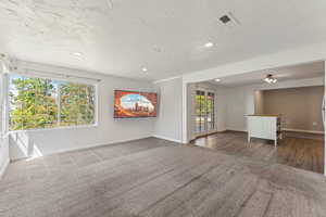 Unfurnished living room with carpet floors, baseboards, french doors, and visible vents