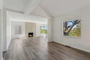 Unfurnished living room with visible vents, baseboards, wood finished floors, and a fireplace