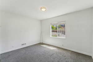 Carpeted spare room with baseboards and visible vents