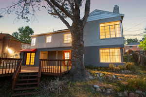 Back of house with fence, a chimney, a wooden deck, and a balcony