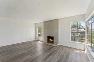 Unfurnished living room with baseboards, a fireplace, wood finished floors, and visible vents