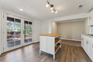 Kitchen with white cabinets, open shelves, dark wood finished floors, and butcher block counters